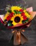 Ramo Aurora de rosas rojas y girasoles vibrantes, envuelto elegantemente en papel de tonos tierra y atado con un lazo de saté