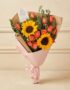 Ramo Beatrice con rosas salmón, girasoles vibrantes y eucalipto, envuelto en papel kraft y rosa, ideal para regalar en cualqu