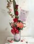 Arreglo floral Solitario Pienso en Ti con rosas rojas, gerberas y follaje en un jarrón de cristal, sobre un fondo elegante de