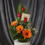 Arreglo floral 'Solitario Tu Recuerdo' con tres rosas rojas, tres gerberas naranjas, follaje verde y flores blancas pequeñas,